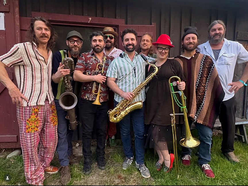 The Valley Moonstompers Society, nine musicians with horns in front of a red barn; Jeff stands at the center with his tenor saxophone